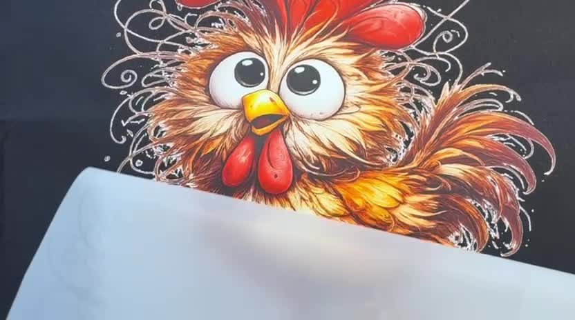 Die Transferfolie wird vom Huhn-Motiv auf einer schwarzen Stofftasche abgezogen