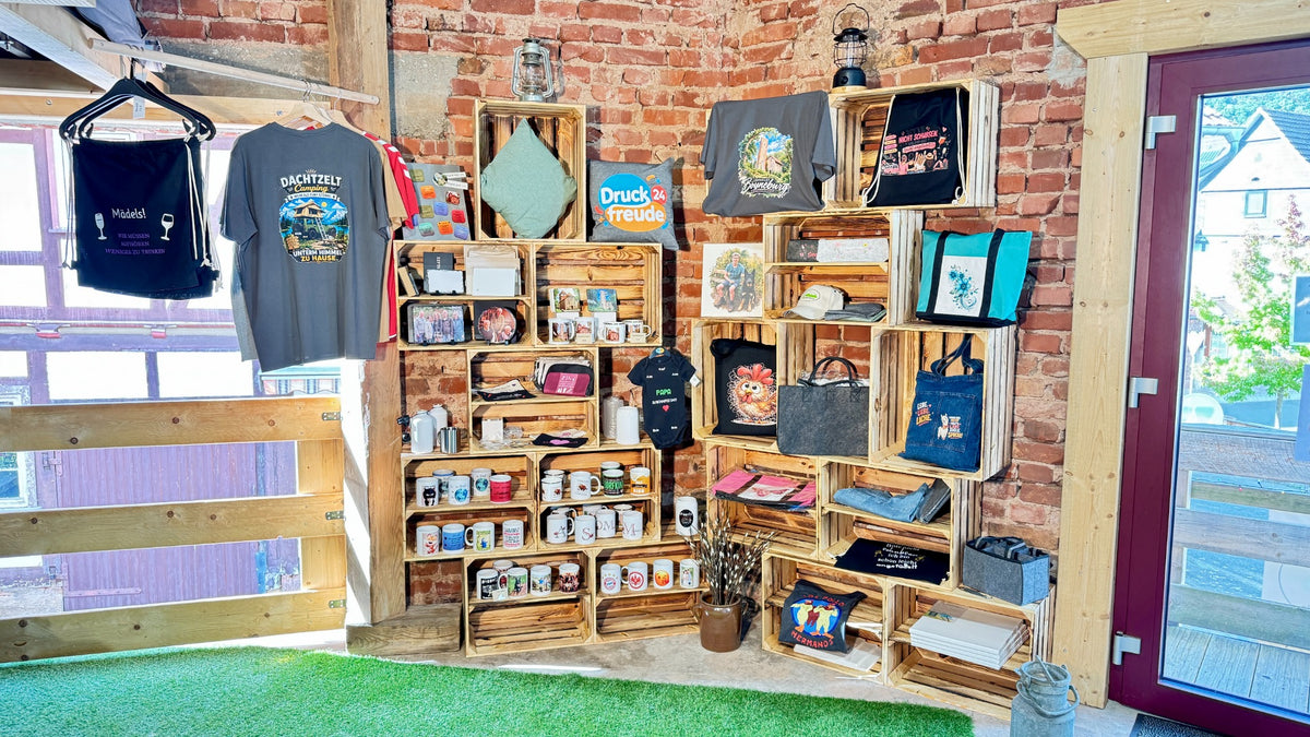 Verkaufsecke der Druckfreude24 in der Dachzeltscheune mit bedruckten T-Shirts, Taschen, Tassen und Fotogeschenken